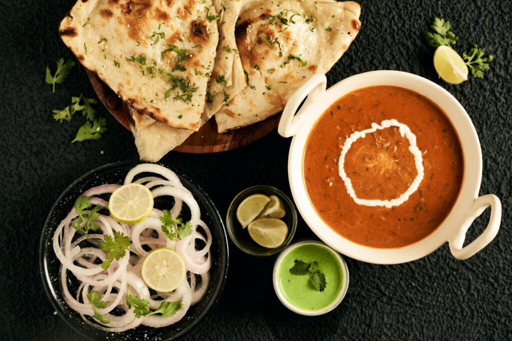 An appetizing Indian meal featuring naan, creamy curry, and fresh condiments.
